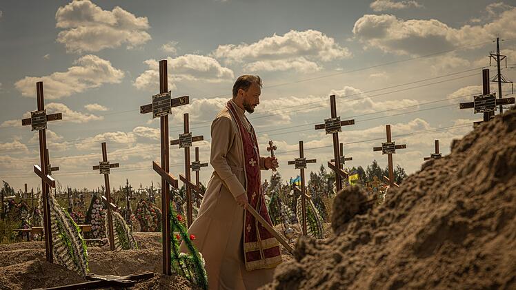 Nach dem russischen &Uuml;berfall auf die Ukraine: Ein Priester bestattet die ukrainischen Zivilisten, die 2022 von russischen Soldaten in Butscha ermordet wurden.