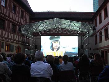 Die Zuschauer sitzen im Innenhof der Kaiserpfalz und sehen auf der Leinwand den Film "Winterkartoffelknödel". Foto: Luisa Hölzel