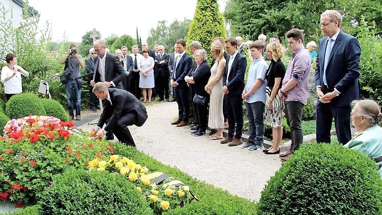 Frank Dassler (stehend) und Harm Ohlmeyer legten im Namen der Firma Adidas einen Kranz am Familiengrab nieder. Foto: Richard Sänger