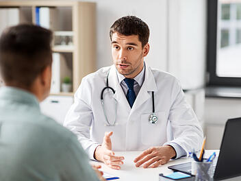 doctor with laptop and male patient at hospital