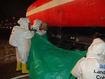 Feuerwehrleute in besonderen Chemie-Schutzanzügen fangen das austretende Gift mit einer Plane auf, bis das Leck geschlossen werden kann.  Fotos: Rainer Lutz