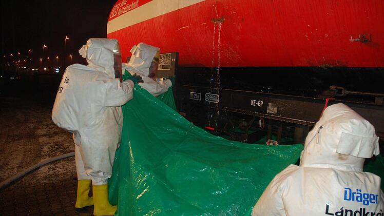 Feuerwehrleute in besonderen Chemie-Schutzanzügen fangen das austretende Gift mit einer Plane auf, bis das Leck geschlossen werden kann.  Fotos: Rainer Lutz