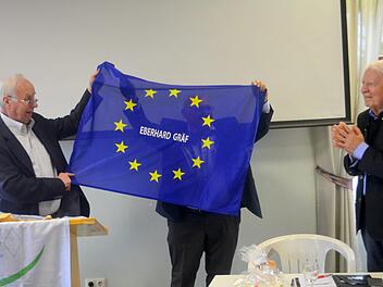 Alfred Wacker, fr&uuml;herer Bad Kissinger  B&uuml;rgermeister, &uuml;bergibt Eberhard Gr&auml;f eine Europafahne als Abschiedsgeschenk. Foto: Arthur Stollberger