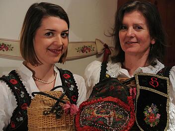 Franziska und Sigrid Schlemmer in Tracht, wie sie sie von Jugend an kennen. Vater Herbert hat großes Talent: Das "Fremnaus-Körble" (links) hat er komplett selbst gefertigt, ebenso die Schürzentasche (rechts) nach historischem Vorbild. Tante Alma schenkte Sigrid zur Hochzeit die Tasche von 1892 (Bildmitte). Fotos: Brigitte Krause