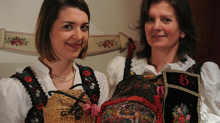 Franziska und Sigrid Schlemmer in Tracht, wie sie sie von Jugend an kennen. Vater Herbert hat großes Talent: Das "Fremnaus-Körble" (links) hat er komplett selbst gefertigt, ebenso die Schürzentasche (rechts) nach historischem Vorbild. Tante Alma schenkte Sigrid zur Hochzeit die Tasche von 1892 (Bildmitte). Fotos: Brigitte Krause