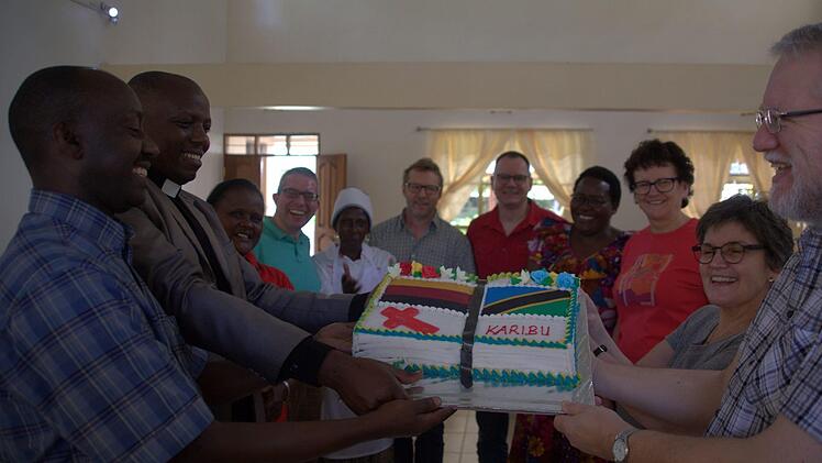 Safari ya Tansania: Zwei Wochen lang besuchte eine Abordnung des Dekanats Michelau den Partner-Distrikt der ELCT. (...) Im mit deutscher Hilfe erbauten Gästehaus in Kingori begrüßten Distriktpastor Anathe Pallangyo und sein Stellvertreter Elirehema Pallangyo (von links) die Gäste (von rechts: Heinz Geyer, Veronika Flierl, Waltraud Leppert, Thomas Kraftzyk, Friedrich Flierl und Heiko Geuß) mit einer Torte in Bibelform, verziert mit den Flaggen beider Länder. Foto: Bettina Knauth