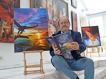 Ralf Vieweg sitzt in seinem Atelier neben dem Originalbild des Covers für sein neues Buch. Foto: Rainer Lutz