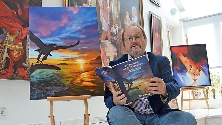 Ralf Vieweg sitzt in seinem Atelier neben dem Originalbild des Covers für sein neues Buch. Foto: Rainer Lutz