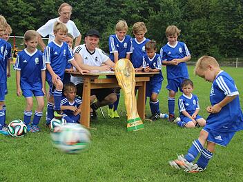 Der sechsjährige Noah Hannweber schießt so scharf, dass der Ball und der rechte Schuh bewegungsunscharf sind. Die anderen Kinder sowie Lorenz Richter (stehend) und Steffen Mahr (am Tisch sitzend) schauen fasziniert zu.  Fotos: Friedwald Schedel