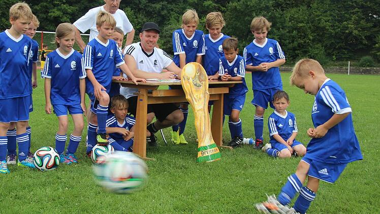 Der sechsjährige Noah Hannweber schießt so scharf, dass der Ball und der rechte Schuh bewegungsunscharf sind. Die anderen Kinder sowie Lorenz Richter (stehend) und Steffen Mahr (am Tisch sitzend) schauen fasziniert zu.  Fotos: Friedwald Schedel