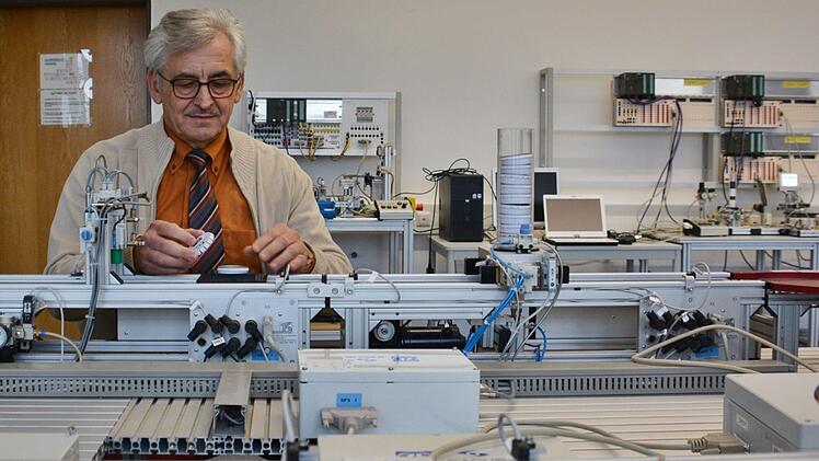 Schulleiter Kurt Hassfurter an einer Schulungsanlage in der Jakob-Preh-Berufsschule in Bad Neustadt. Diese Anlage erkennt über Strichcode den Arbeitsvorgang. Hier entstehen kleine Plastikdöschen, die sogar noch mit verschiedenfarbigen Kügelchen gefüllt werden. Foto: Hanns Friedrich