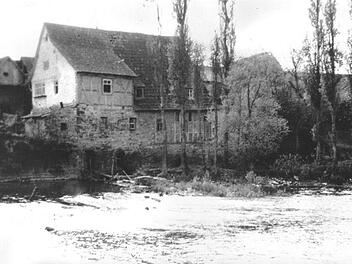 Das Foto (vermutlich um 1920/1930 aufgenommen) zeigt die Fuschter Mühle von Westheim aus gesehen. Im Vordergrund ist der Mühlgraben mit dem verfallenen Wehr erkennbar.  Foto: Archiv Lothar Pfülb