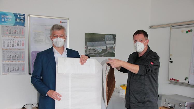 Werkleiter Peter Rüger (rechts) zeigt den ersten Produktionsschritt, in dem mehrere Lagen zu einem Schlauch verklebt werden. Links hält Geschäftsführer Volker Reimer einen fertigen Sack mit Boden.  Foto: Ralf Ruppert