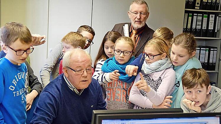 Georg Köth von der Bauverwaltung zeigt den Kindern der 4. Klasse aus Lauter und Bürgermeister Waldemar Bug (hinten) am Bildschirm verschiedene Grundstückspläne. Foto: Kathrin Kupka-Hahn