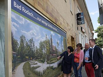 Oh, wie ist das schön: Nur wenige Schritte von der Coburger Straße entfernt, ist der Wallgraben ein Schmuckstück der Stadtentwicklung. Damit Einheimische und Kurgäste das auch registrieren, hat die Stadt ein Schaufenster mit einem großen Wallgraben-Bild beklebt. Corina Trier, Christina Wolf, Dieter Weil und Tobias Ehrlicher (von links) gefällt das, was sie darauf sehen. Foto: Berthold Köhler