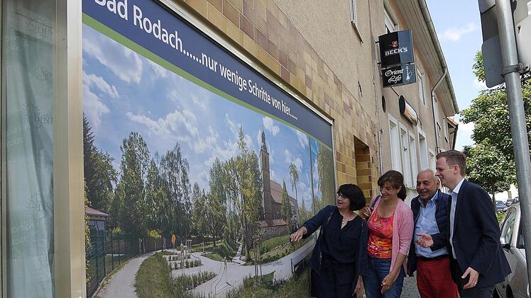 Oh, wie ist das schön: Nur wenige Schritte von der Coburger Straße entfernt, ist der Wallgraben ein Schmuckstück der Stadtentwicklung. Damit Einheimische und Kurgäste das auch registrieren, hat die Stadt ein Schaufenster mit einem großen Wallgraben-Bild beklebt. Corina Trier, Christina Wolf, Dieter Weil und Tobias Ehrlicher (von links) gefällt das, was sie darauf sehen. Foto: Berthold Köhler
