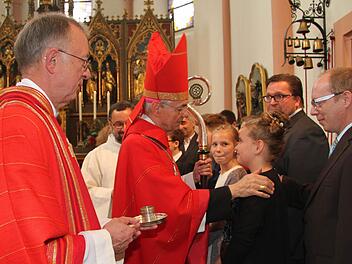 Nachdem der Erzbischof einige persönliche Worte an die Firmlinge gerichtet hatte, zeichnete er ihnen ein Kreuz auf die Stirn. Dekan Hans Roppelt hielt dafür das Chrisamöl bereit. Foto: Sonny Adam
