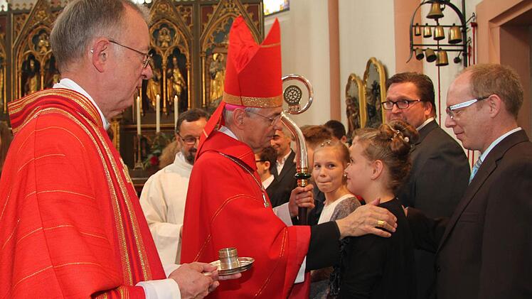 Nachdem der Erzbischof einige persönliche Worte an die Firmlinge gerichtet hatte, zeichnete er ihnen ein Kreuz auf die Stirn. Dekan Hans Roppelt hielt dafür das Chrisamöl bereit. Foto: Sonny Adam