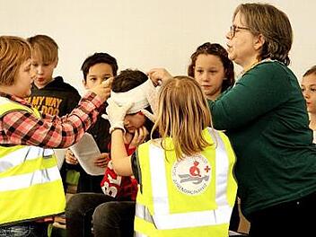 Auch das Anlegen eines Kopfverbandes, hier mit Unterstützung von Lehrerin Helga Hertlein, will gelernt sein. Foto: Günther Geiling