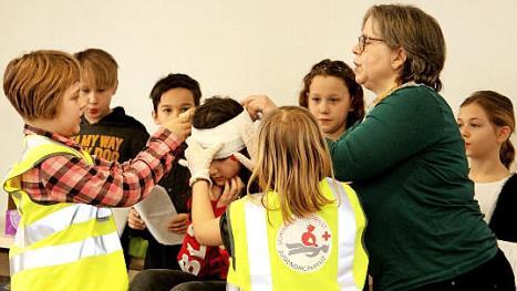 Auch das Anlegen eines Kopfverbandes, hier mit Unterstützung von Lehrerin Helga Hertlein, will gelernt sein. Foto: Günther Geiling