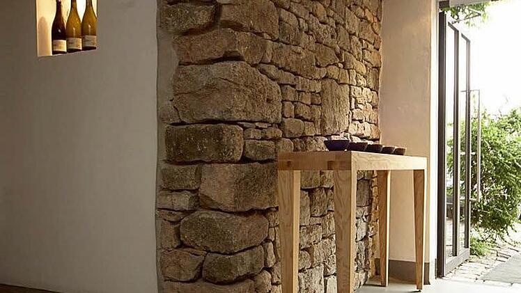 Weingut Brennfleck: Seiteneingang mit Natursteinwand und Tisch. Foto: Weingut Brennfleck