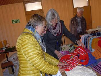 Theresia Kiesel zeigt Besuchern die ausgestellten Stricksachen beim Basar der Kolpingsfamilie zugunsten von Rumänien. Foto: Anneliese Albert