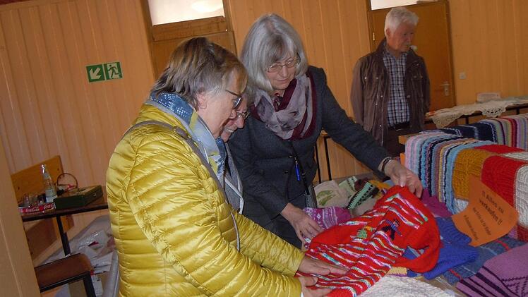 Theresia Kiesel zeigt Besuchern die ausgestellten Stricksachen beim Basar der Kolpingsfamilie zugunsten von Rumänien. Foto: Anneliese Albert