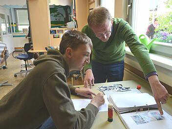 Der "Seitenwechsler" Jan-Dirk Peters (rechts) klebt mit Bewohner Patrick Bilder in dessen Berichtsheft ein. Foto: Larissa Händel