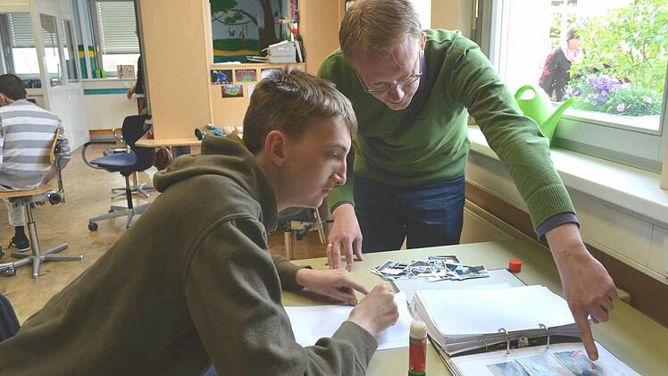 Der "Seitenwechsler" Jan-Dirk Peters (rechts) klebt mit Bewohner Patrick Bilder in dessen Berichtsheft ein. Foto: Larissa Händel