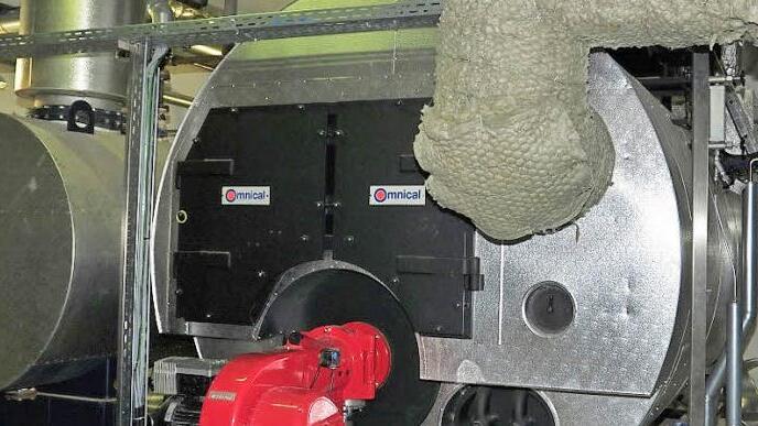 Die Firma Maintal Konfitüren GmbH in Haßfurt hat auch in einen neuen Dampfkessel (im Bild) investiert. Die Wärme, die in der Mikrogasturbine durch die Verbrennung entsteht, wird über ein isoliertes Rohr (oben rechts) in einen Heizraum des neuen Kessels geleitet und erzeugt dort Dampf.  Fotos: Ulrike Langer