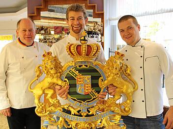 Gemeinsam stolz auf eine lange Firmen- und Familientradition (von links): Wolfgang Schubart mit seinen Söhnen Maximilian und Christian sowie dem Wappen, das ihr Café als einstigen Hoflieferanten ausweist. Fotos: Oliver Schmidt