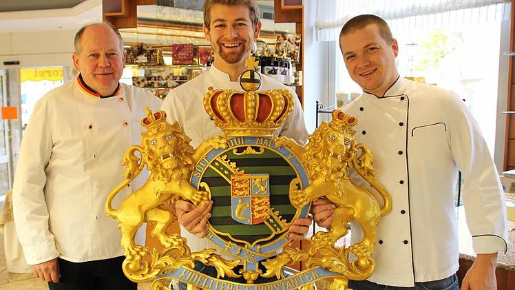 Gemeinsam stolz auf eine lange Firmen- und Familientradition (von links): Wolfgang Schubart mit seinen Söhnen Maximilian und Christian sowie dem Wappen, das ihr Café als einstigen Hoflieferanten ausweist. Fotos: Oliver Schmidt