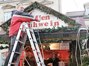 Die Bäckerei Möckel baut ihren Stand seit 1978 auf dem Weihnachtsmarkt auf: Christian Möckel (auf der Leiter) bringt noch eine Lichterkette an, während Ursula Möckel die Tassen für den Glühwein einräumt. Hilfe bekommen sie von Klaus Dragon.  Fotos: Thomas Heuchling
