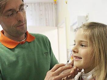 So  könnte eine Grippeimpfung ohne Spritze  aussehen: Der Impfstoff für Kinder wird  in die Nase gesprüht. Kinderarzt Patrick Muzzolini zeigt bei der siebenjährige Marlene, wie es aussehen könnte.   Foto: Vanessa Schneider