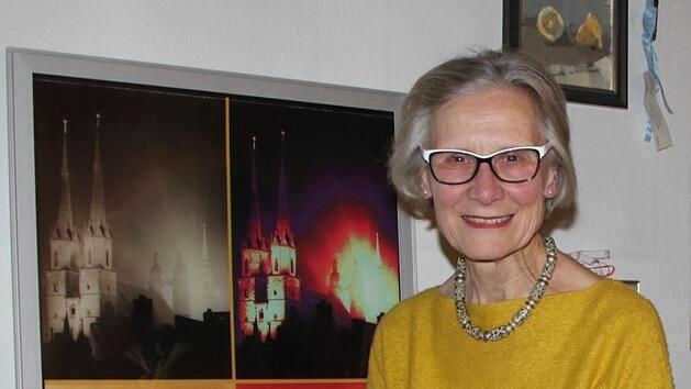 Adelheid Zimmermann sitzt vor einer Collage, die sie aus Fotografien ihres Vaters angefertigt hat. Sie zeigen dessen Heimatstadt Halle. Foto: Ulrike M&uuml;ller