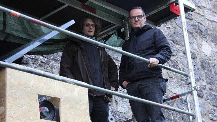 Raphael Schardt und Rotary-Präsident Rolf Hering in luftiger Höhe auf dem Gerüst im Wallgraben. Mit einem Hochleistungsbeamer, der sich in der Holzkiste befindet, wird die Videoprojektion "Sturm auf Kronach" an die Wallmauer gestrahlt.  Fotos: Friedwald Schedel