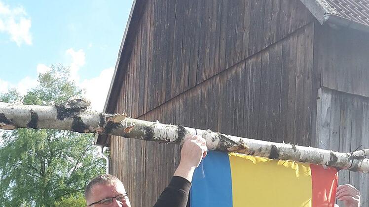 Carsten Struß, Ortssprecher von Volkers-Nord, hängt die Nordenhamer Fahne an den Süd-Volkerser Maibaum.  Heike Kötzner