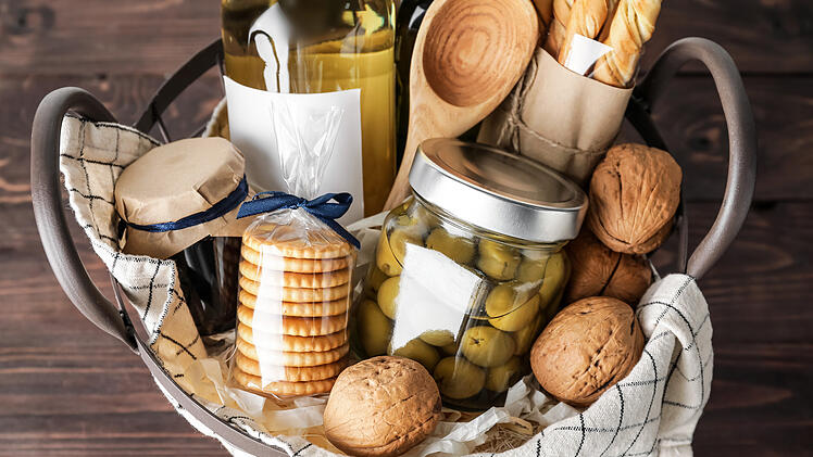 Gift basket with products on wooden table, closeup