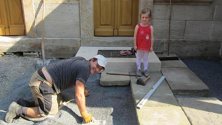 Ralf Hofmann verlegt die Sandsteinplatten am Hauseingang, Tochter Sophia verfolgt's argwöhnisch.