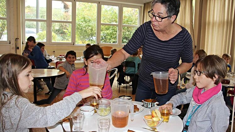 Kira, Paula und Maja (von links) bekommen von Anita Platzer Getränke zum Mittagessen. Die drei jungen Damen am Tisch bedauern, dass sie im neuen Mensa- und Betreuungsgebäude nicht mehr dabei sind, weil sie dann nicht mehr Grundschülerinnen sein werden. Foto: Helmut Will