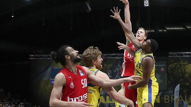 Mit einem Hakenwurf &uuml;ber den Braunschweiger Joseph Lawson hinweg versucht Christian Sengfelder (hinten) zu punkten. Vorne ringen die beiden Center Assem Marei und Scott Eatherton um die bessere Position f&uuml;r den Rebound. Foto: Susanne H&uuml;bner