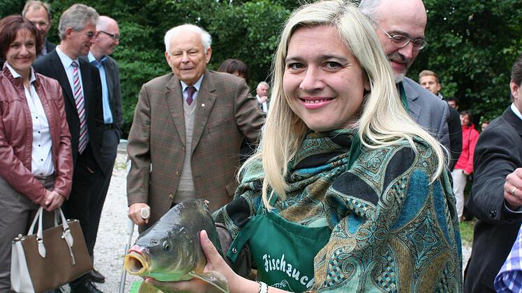 Melanie Huml zeigt einen Karpfen.