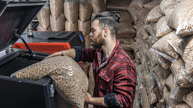 Mann f&uuml;llt Pellets in Heizung.