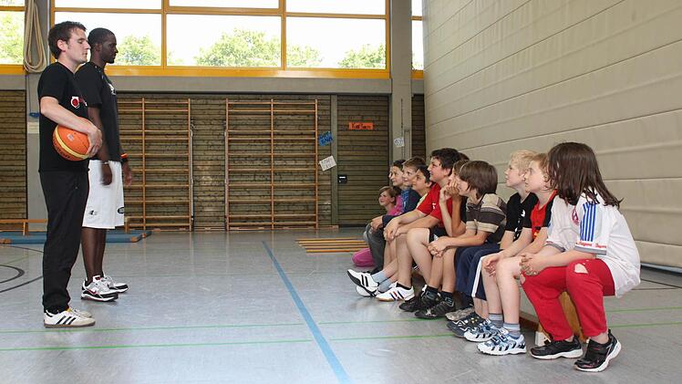 Sebastian Böhnlein (links) und Rob Ferguson (rechts)  von den Brose Baskets besprechen mit den Schülern den Parcours.