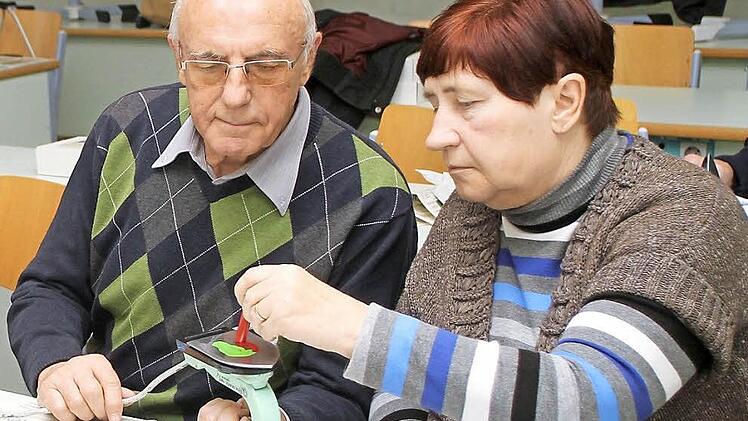 Günther Schnabel hält das Mal-Eisen, während seine Frau Gerda die Farben auf die heiße Fläche aufträgt. Foto: Günther Geiling