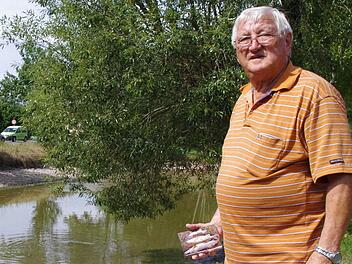Erwin Dannreuther am Gundelsdorfer Teich. In der Hand hält er Fotos von verendeten Fischen. Foto: Marco Meißner