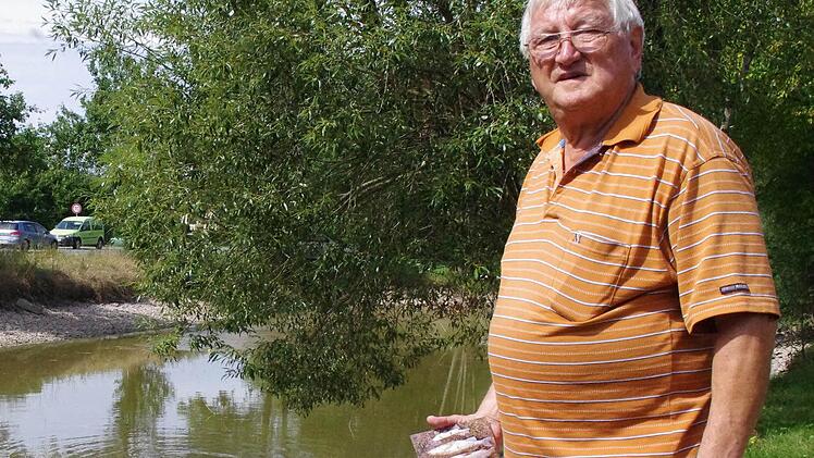 Erwin Dannreuther am Gundelsdorfer Teich. In der Hand hält er Fotos von verendeten Fischen. Foto: Marco Meißner