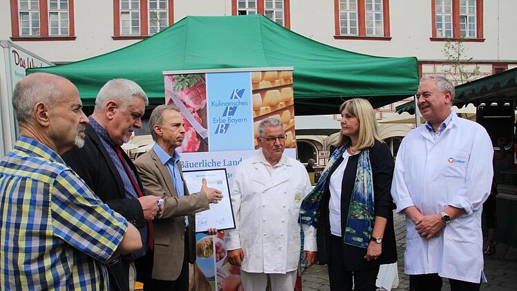 Der formelle Akt mit Landtagsabgeordnetem Jürgen Heike, Oberbürgermeister Norbert Tessmer, Wolfgang Filter vom Verein Kulinarisches Erbe Bayern, Joachim Grosch, Sprecher der Marktkaufleute, Bürgermeisterin Birgit Weber, Fleischerinnungs-Obermeister Ralf Luther (von links). Foto: Simone Bastian