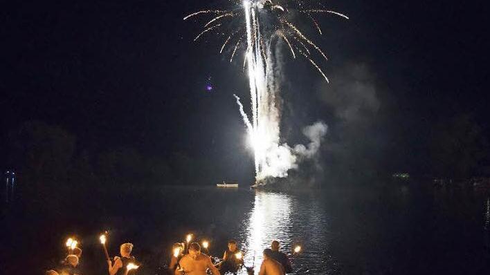 Die Fackelschwimmer haben den See durchschwommen und steigen aus dem Wasser.  Foto: Andreas Welz