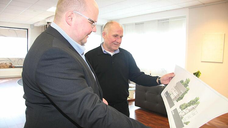 Matthias Schirmer (links)und Dietmar Müller betrachten einen ersten Plan des Architekturbüros Schmidt, der zeigt, was aus den Genossenschaftswohnblöcken werden könnte.